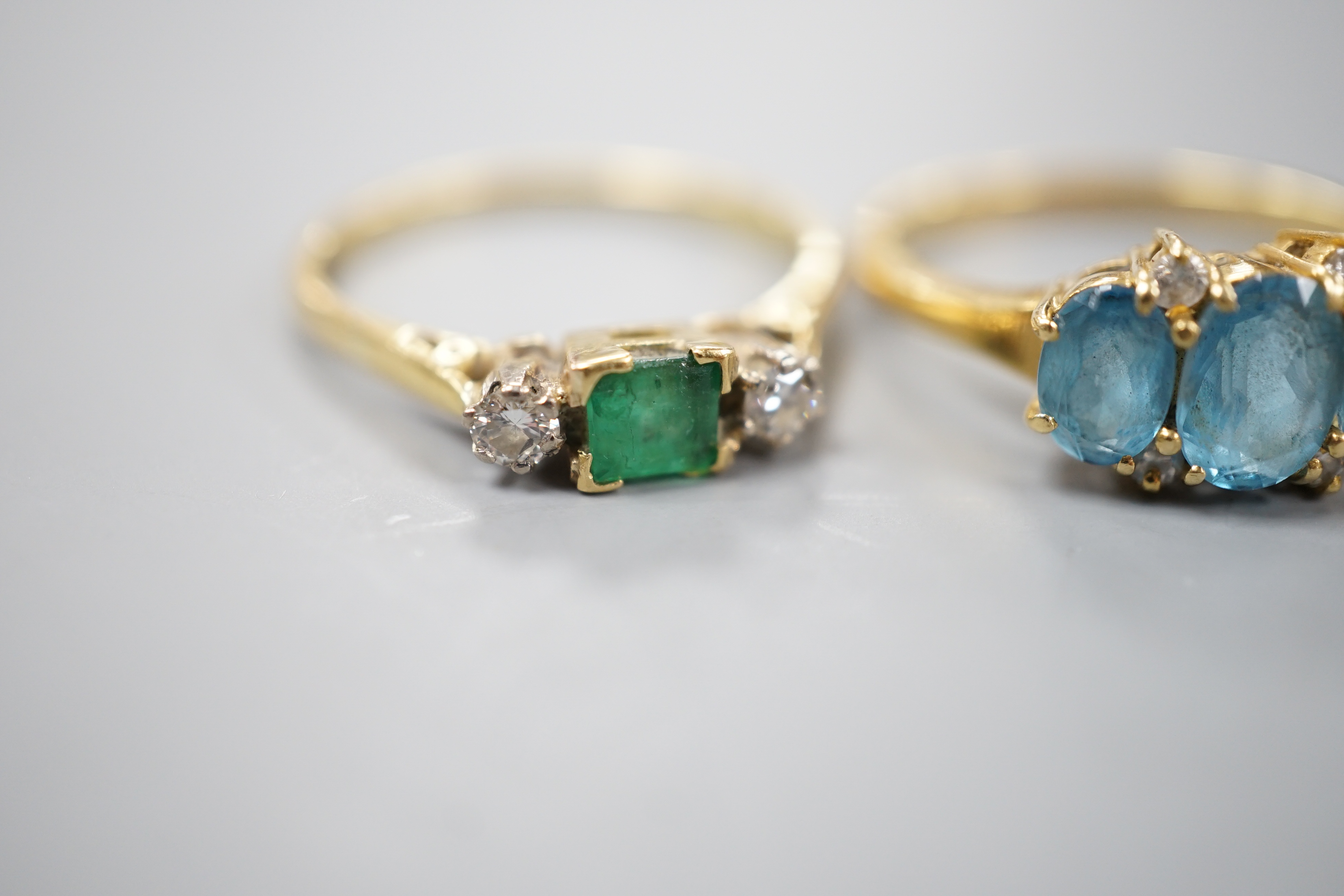 Three assorted 18ct and gem set dress rings, including emerald and diamond three stone, size Q/R, gross 11.7 grams.